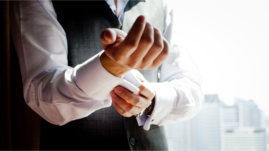 Homme en tenue élégante ajustant le poignet de sa chemise blanche avant un événement formel