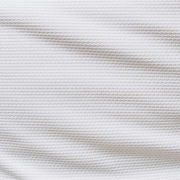 Gros plan sur un tissu blanc texturé illustrant la qualité du tissu pour une chemise de mariage