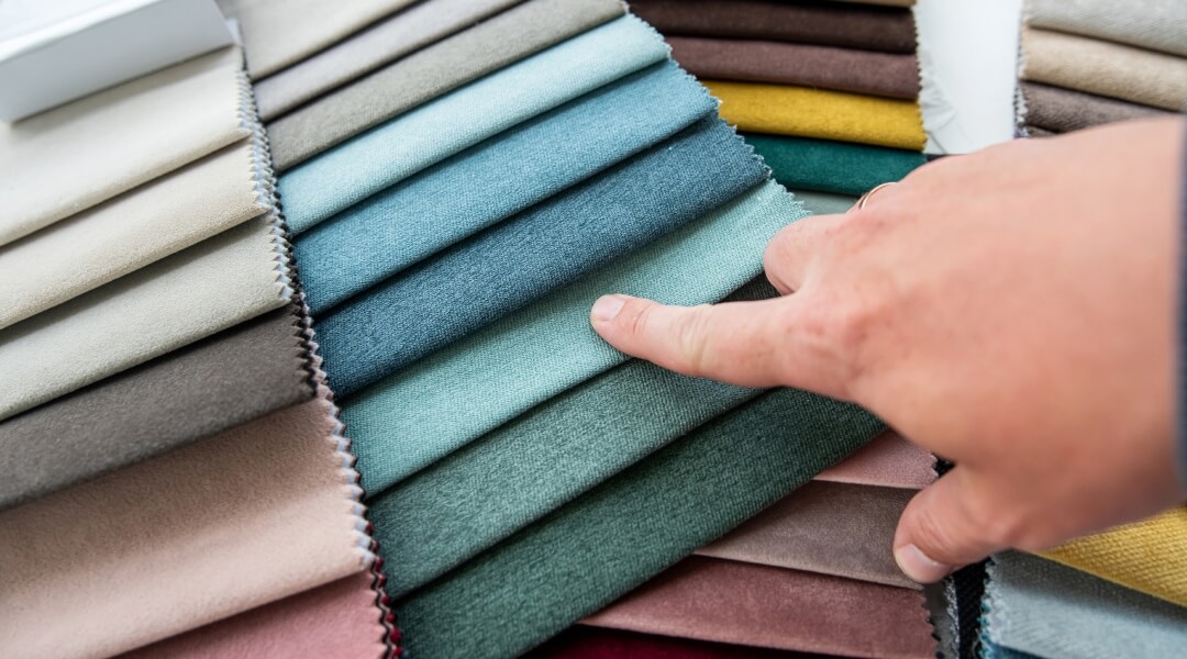 Une vue rapprochée et ordonnée d'échantillons de tissus de laine et de lin dans des teintes modernes comme le bleu ciel, le vert olive, le terracotta et le gris, parfaits pour choisir la couleur d'un costume de mariage.