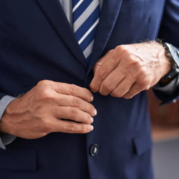 Un homme en costume ajuste sa cravate, prêt pour un mariage.