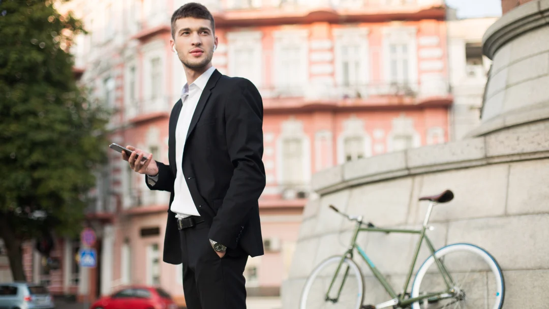 Un homme en costume se tient à côté d'un vélo, illustrant un style élégant à Paris.