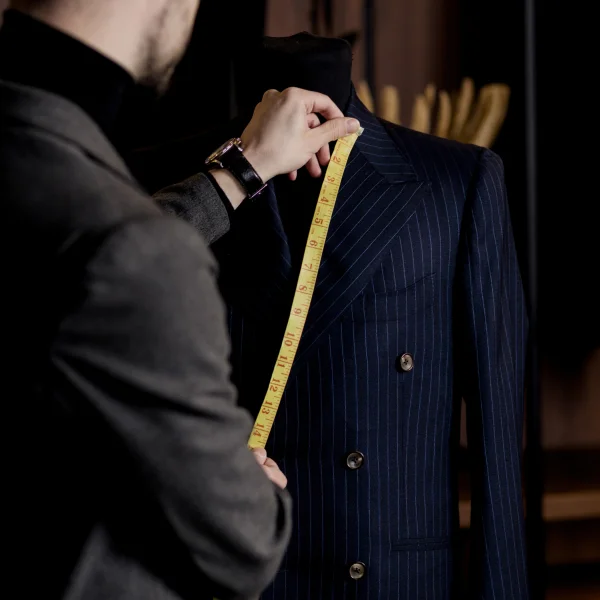 Un homme mesure un costume sur un mannequin dans un atelier de tailleur à Paris. 
