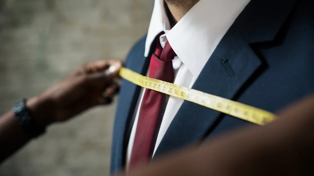 Un homme mesure son costume avec un mètre ruban dans un atelier de tailleur à Paris.
