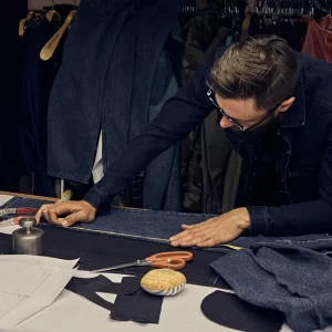 Un homme travaillant sur une table dans un atelier de tailleur à Paris.
