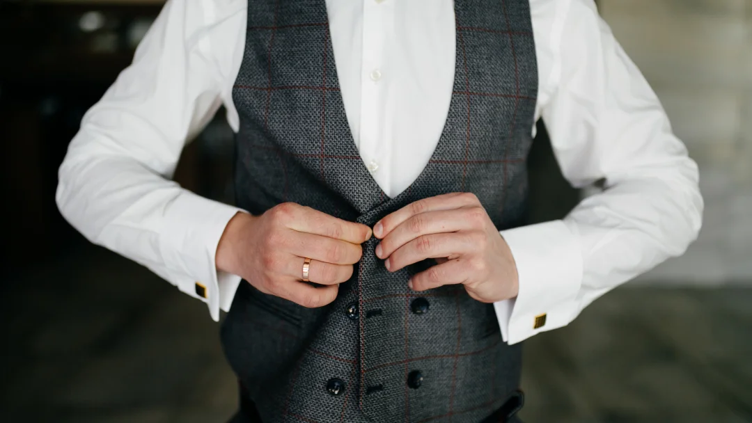 Un homme en costume ajustant son gilet, illustrant un service de costume sur mesure pour un mariage.