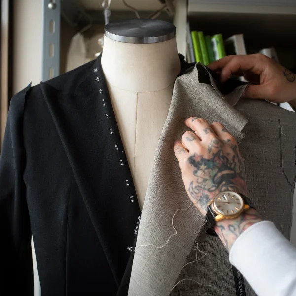 Un homme tatoué ajuste un costume de mariage sur mesure.
