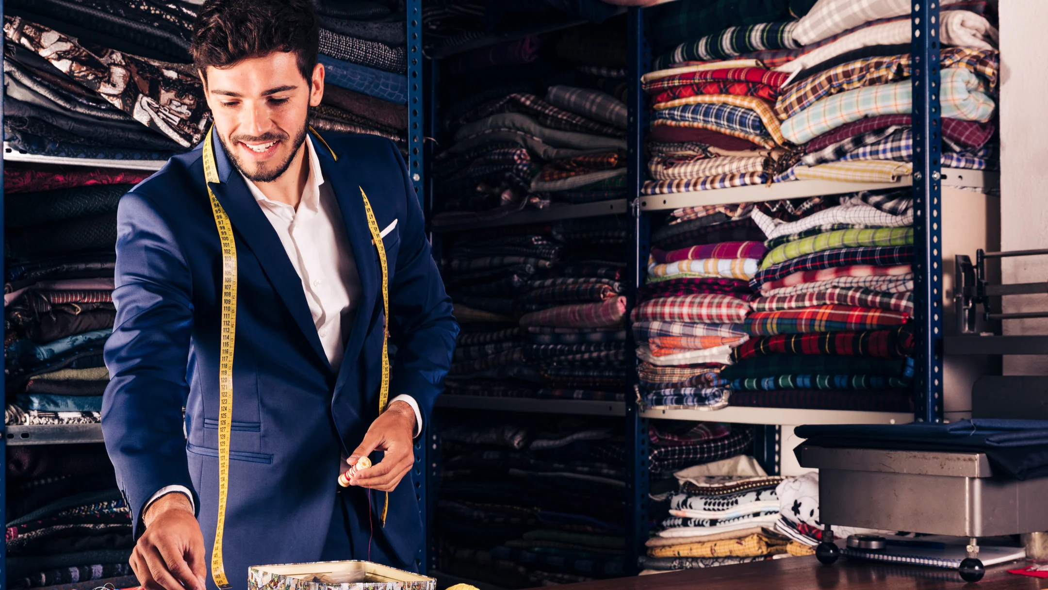 Un homme en costume mesure quelque chose dans un placard, illustrant un moment de préparation pour un costume croisé.