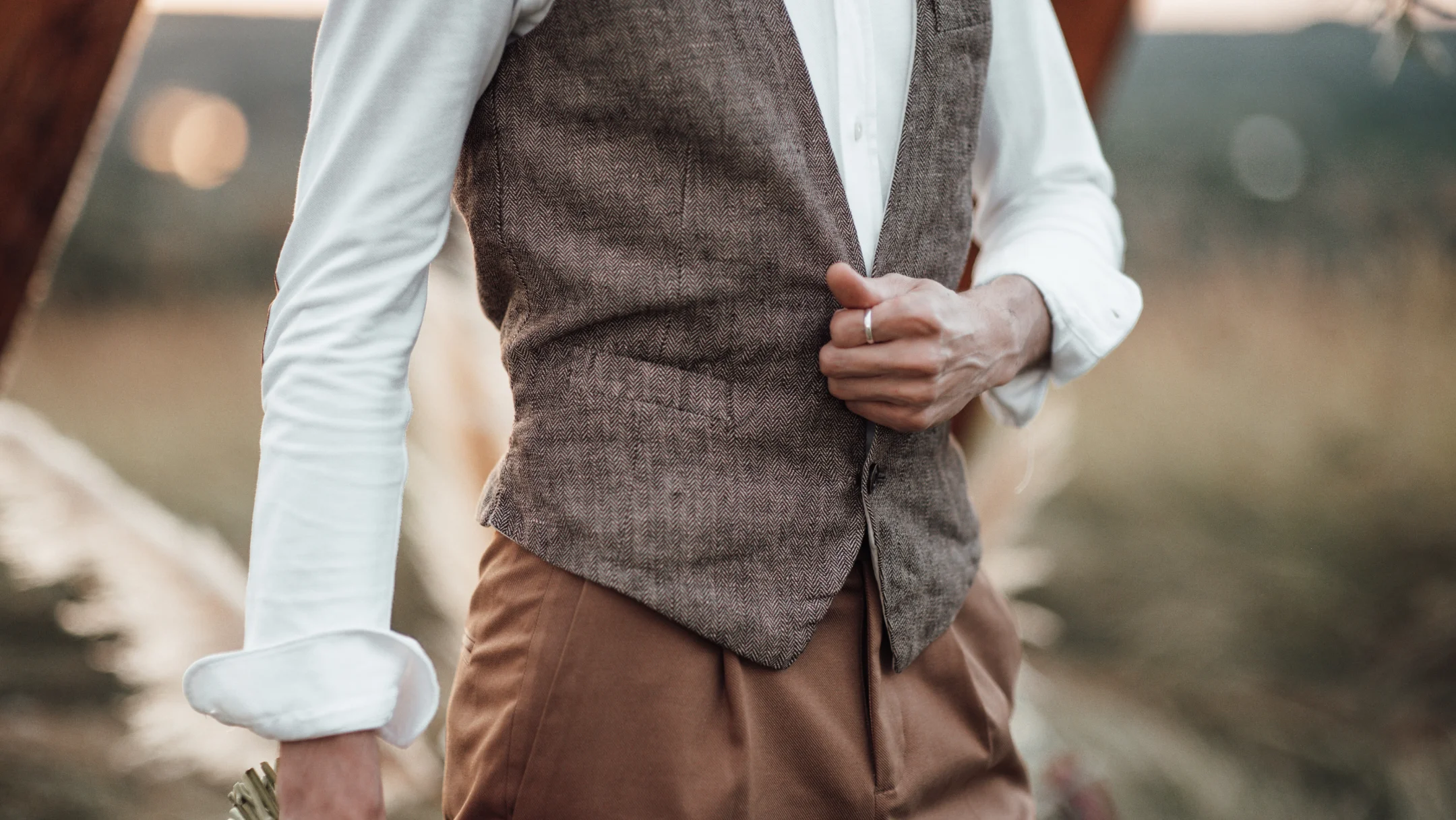 Un homme en costume ajuste sa cravate, prêt pour un mariage.