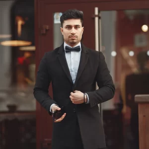 Un homme en costume italien, élégant, se tient debout avec une posture confiante.