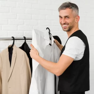 Un homme souriant tient une chemise, prêt pour son mariage.