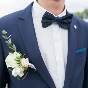 Un homme en costume bleu avec une boutonnière florale, prêt pour un mariage sur mesure.