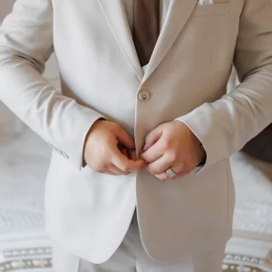 Un homme en costume en lin ajuste sa cravate avec soin.