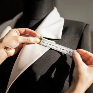 Une personne mesure un veston de costume italien avec un mètre ruban.