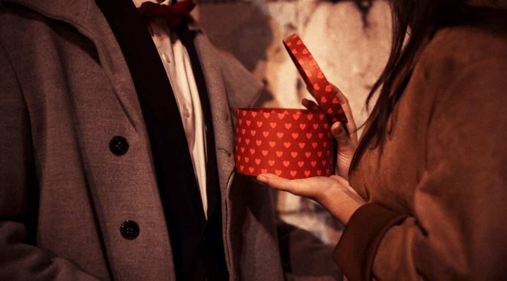 Un homme et une femme tiennent une boîte rouge, symbolisant des cadeaux de Saint-Valentin élégants.