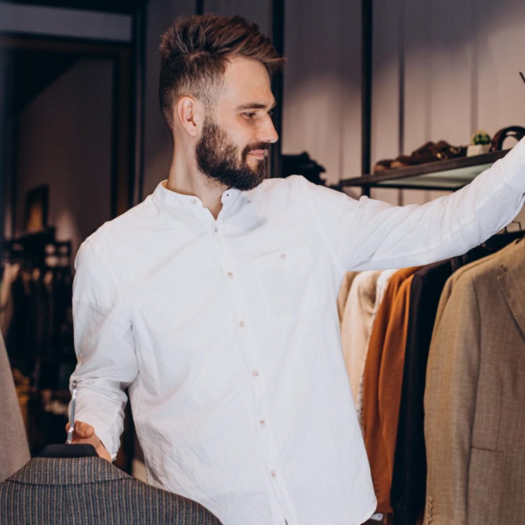 Homme comparant des vestes de costume en boutique pour choisir entre flanelle et tweed selon le style, le confort et l’usage.