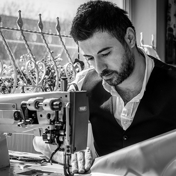 Tailleur expérimenté travaillant sur une machine à coudre dans son atelier, illustrant le savoir-faire et la fiabilité d’un professionnel du sur-mesure.