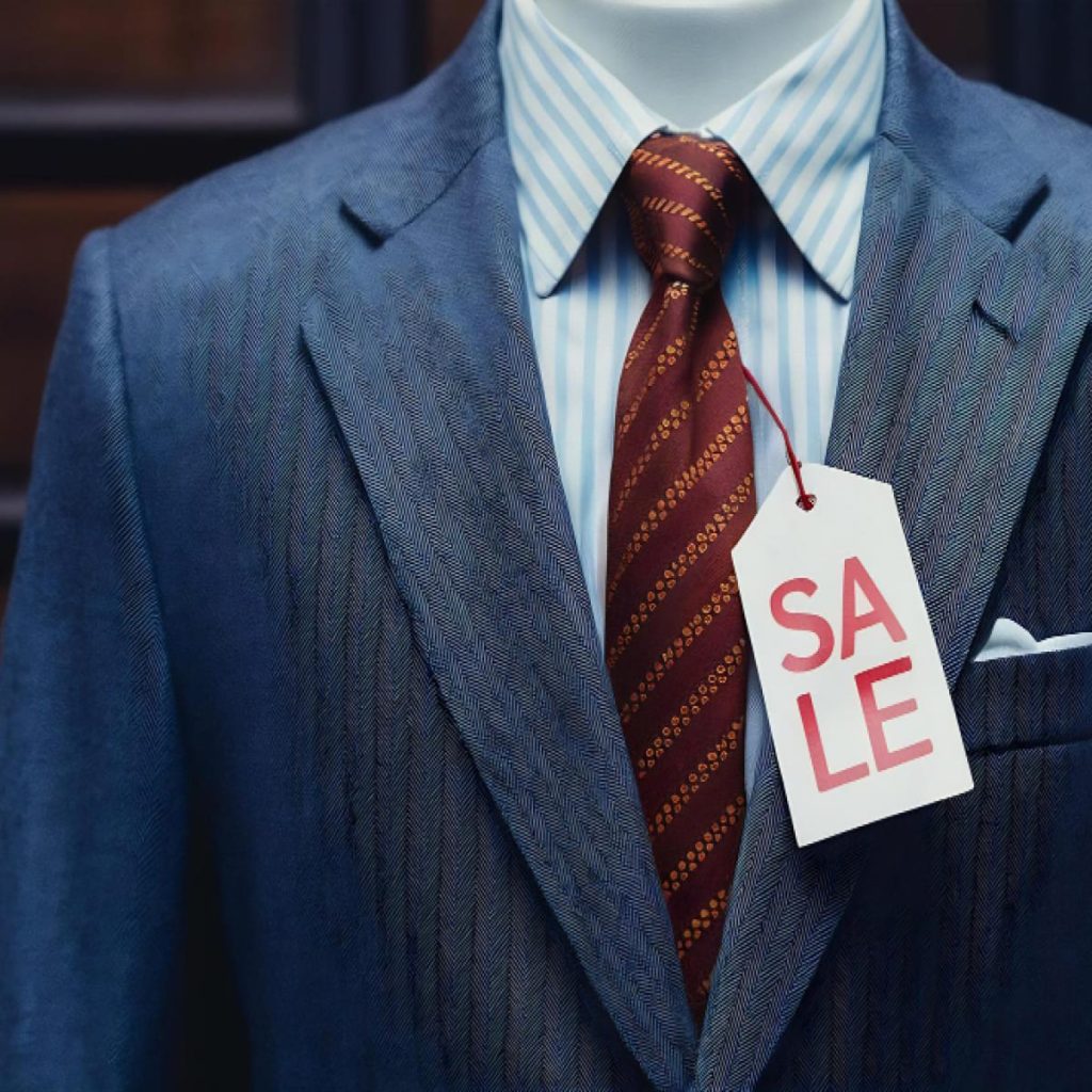 Détail d’un costume avec étiquette en vente illustrant l’impact du tissu sur le prix final d’un costume sur mesure.
