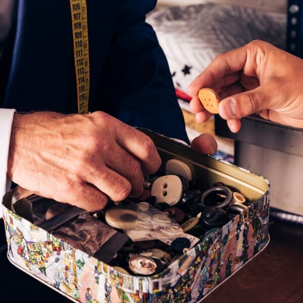 Une vue rapprochée des finitions haut de gamme d'une veste personnalisée, montrant des boutons artisanaux, une boutonnière cousue main et la texture distinctive du tissu de luxe.