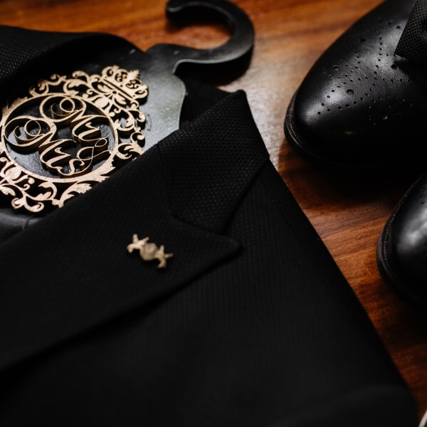 Une vue rapprochée et artistique des détails d'un costume haut de gamme, mettant l'accent sur la texture du tissu, une boutonnière délicatement travaillée et l'ajustement parfait du col et de la chemise.