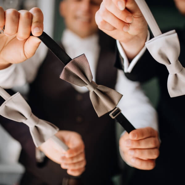 Une vue rapprochée mettant en valeur un nœud papillon en soie, des boutons de manchette étincelants et une pochette de costume soigneusement pliée, disposés élégamment pour compléter une tenue de mariage haut de gamme.